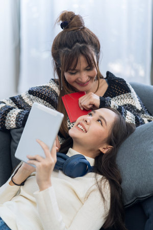 Two Asian woman planning a trip and holding a passport in the living room.の写真素材