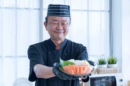 The salmon slice is in the hands of the chef. Asian chef slice salmon by knife.の写真素材