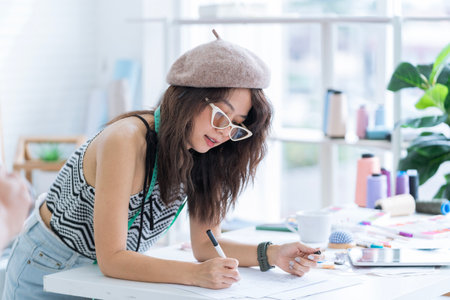 Fashion designer woman working on her designs in the studio. Asian Women making clothing pattern. Young seamstress at work.の写真素材