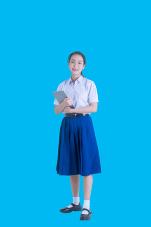 Asia beautiful girl holding a tablet. Happy teen high school student on blue background.の写真素材