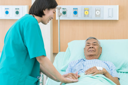 Senior asian male patient smiling with nurse who come to visit he on bed in hospital. Doctor or nurse visiting and cheering senior man.の写真素材