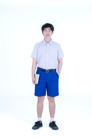 A student in a Thai uniform is standing straight and holding a book. asia thai high school student uniform boy holding a book.の写真素材