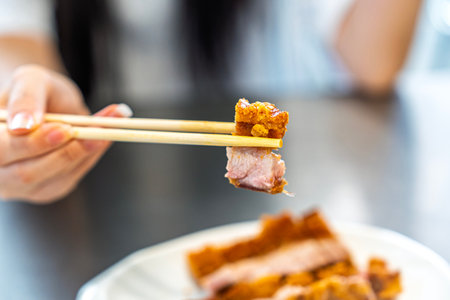 Young woman is picking up crispy pork with chopsticks in a Chinese restaurant.の写真素材