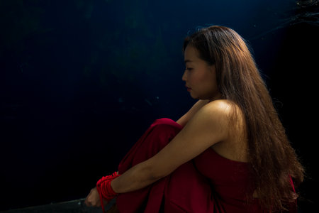 A woman in a red dress is being held captive.の写真素材