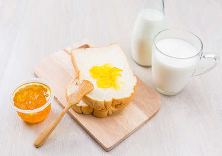 Breakfast with milk, bread and jam on the wooden tableの写真素材