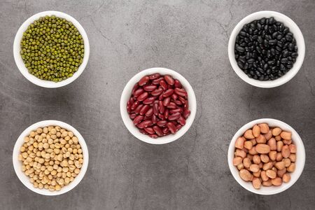 Grains beans in the white bowl placed on the black cement floor. Top view.