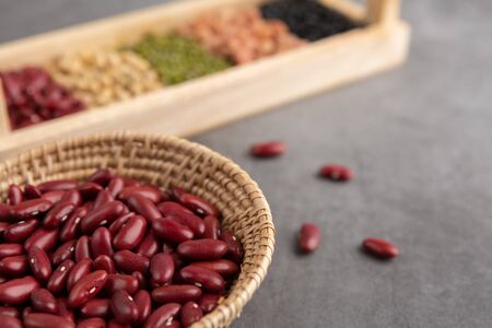 Red beans and grains in the wooden basket and in the wooden tray placed on the black cement floor. High angle view.の写真素材
