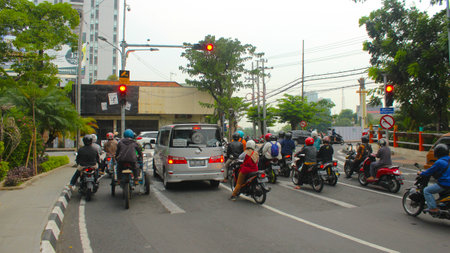 motorbikes and cars stop at traffic lights