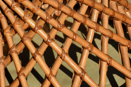 Rattan stool with no vertical structure except bigger size of rattan woven skew up like parabolic curve. Exposed to sunlight privides interesting pattern.の写真素材