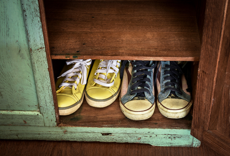 Sneakers in shoes storage cabinet.Two pairs of sneakers kept in vintage wooden cabinet.の写真素材