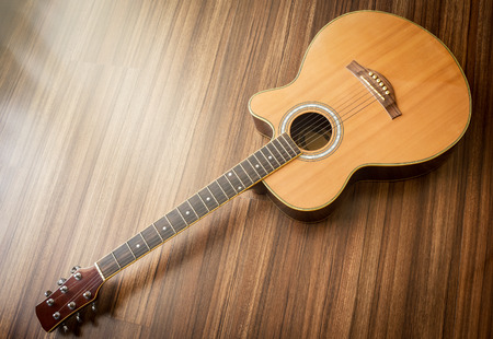 Acoustic guitar laid on wooden floor background.Soft light effect added.の写真素材
