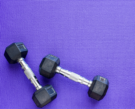 Two dumbbells weight 3 kilogram each on purple color Yoga mat background.の写真素材