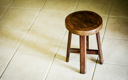 Solid low wooden stool on light color tile floor. Art studio round stool.の写真素材