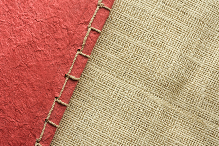 Contrast abstract background of red natural paper notebook on hemp textile.の写真素材