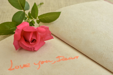 Fresh pink rose on natural paper note book page with hand writingの写真素材
