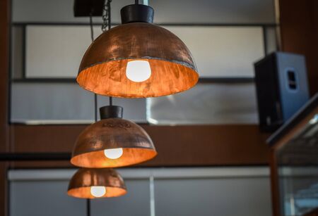 Vintage lighting style in a cafeteria using round copper lampshade hanging from the ceiling.の写真素材