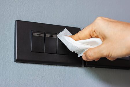 Thai woman wipes her hands with an alcohol towel washing switch. Coronavirus prevention for hand hygiene corona virus protection. COVID-19 prevention sanitizing inside.の写真素材