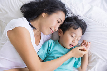 Authentic close up of happy mother and her son in a bed. Concept of new generation, family, parenthood, authenticity, connectionの写真素材
