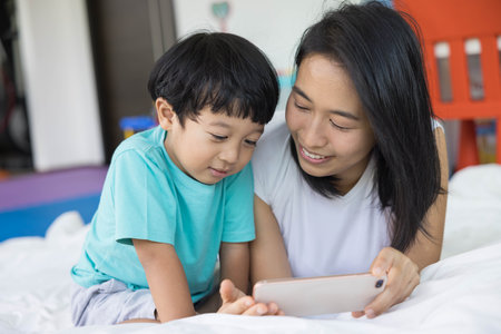 close up of happy mother and her son Taking pictures or selfie or video call or relatives in a bed. Concept of new generation, family, parenthood, authenticity, connectionの写真素材