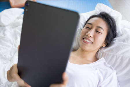 woman using digital tablet in a bed at home. The use of concept of new generation, family,...