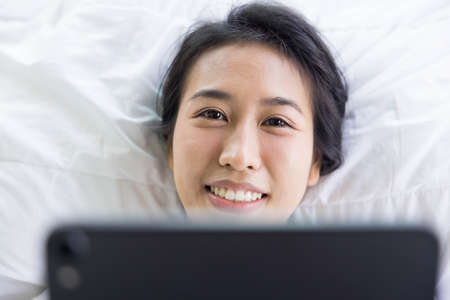 woman using digital tablet in a bed at home. The use of concept of new generation, family, parenthood, authenticity, connection, technologyの写真素材