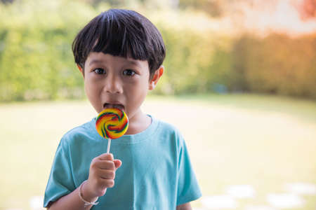 A boy in a green shirt is enjoying his colorful round lollipop.の写真素材