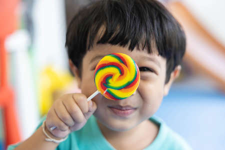 A boy in a green shirt is enjoying his colorful round lollipop.の写真素材
