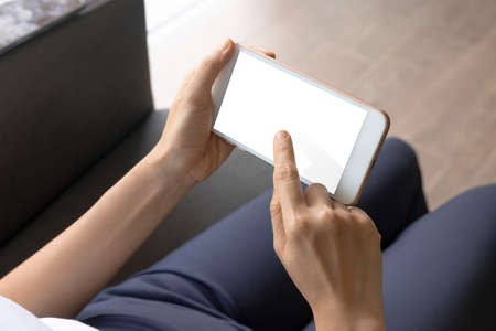 Close-up woman of hand held with smart phone white screen on sofa in the living room. Concept of...