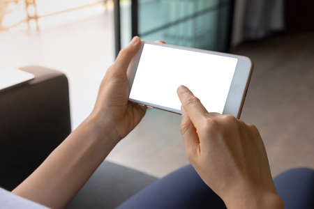 Close-up woman of hand held with smart phone white screen on sofa in the living room. Concept of technology, connection, communicationの写真素材