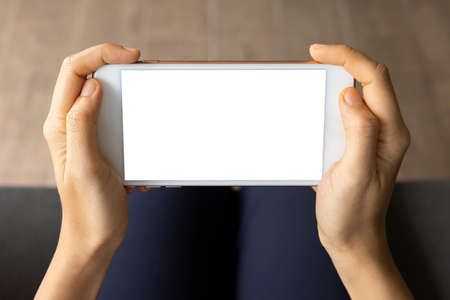 Close-up woman of hand held with smart phone white screen on sofa in the living room. Concept of technology, connection, communicationの写真素材
