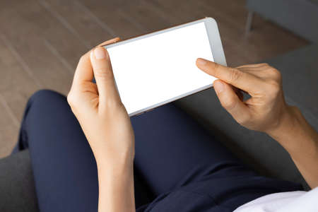 Close-up woman of hand held with smart phone white screen on sofa in the living room. Concept of technology, connection, communicationの写真素材