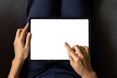 Close-up woman of hand held with digital tablet white screen on sofa in the living room. Concept of technology, connection, communication.の写真素材