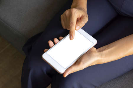 Close-up woman of hand held with smart phone white screen on sofa in the living room. Concept of technology, connection, communicationの写真素材