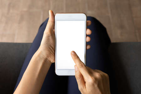 Close-up woman of hand held with smart phone white screen on sofa in the living room. Concept of technology, connection, communicationの写真素材