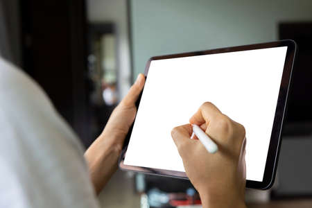 Close-up woman drawing of hand held with digital tablet white screen on sofa in the living room. Concept of technology, connection, communication.の写真素材