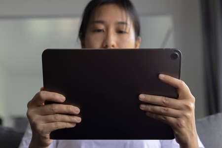 Close-up woman of hand held with digital tablet on sofa in the living room. Concept of technology, connection, communication.の写真素材