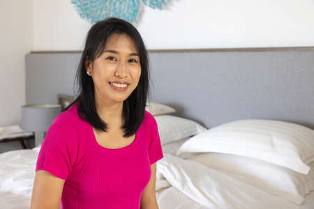 A woman sit on the white bed at home. Concept about social, people, business. medium shot.の写真素材
