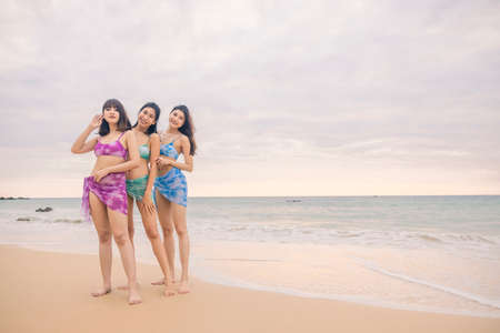 Three young women friends happily wear this bikini on a beach in Nai Thon Beach, Phuket Province, Thailand. Portrait of happy young woman smiling at sea. Concept about Travel, happiness, nature.の写真素材
