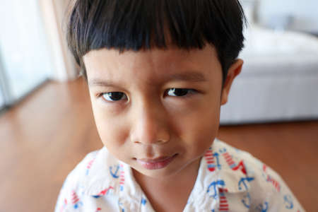 Close up. Portrait a Asian boy with bangs hair cheerful is so adorable child, wearing white shirt, Active 4-5 years old kid smiling funny shocked face and looking at camera.の写真素材