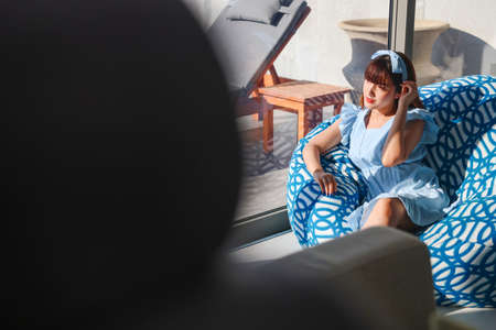 Portrait woman relaxing enjoying luxury lifestyle on blue soft sofa at home. Beautiful young lady Asian Caucasian female model, thinking looking happy up smiling cheerful of stress free weekend.の写真素材