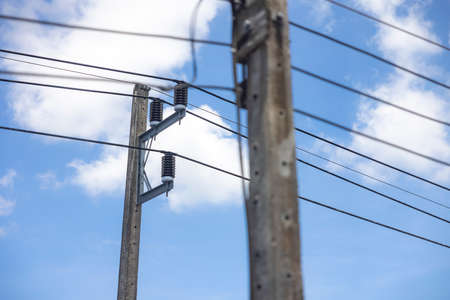 Electric pole and power line on a clear day with blue sky and white clouds in the background.の写真素材
