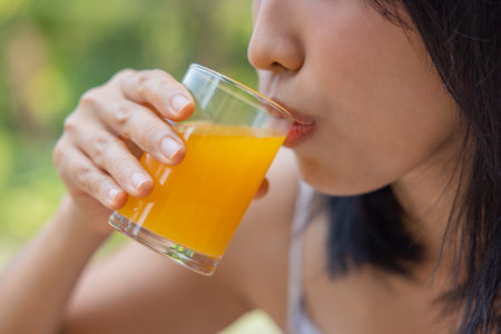 Close up of woman drink orange juice. Girl enjoy fruit juice for lunch, wellbeing diet concept. Concept of health.の写真素材
