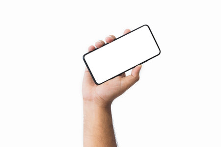 Male hand holding black smartphone with blank screen and modern frameless design two positions angled copy space isolated on white background. close-up hand of man hold mobile phone. Space for text.の写真素材