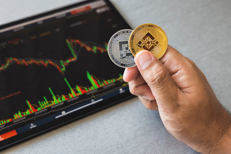 Close-up hand of man holding crypto coin on chart in tablet background. Blockchain technology finance future. Male hold BNB. concept about business, finance, trade, economy, banking, investment.の写真素材