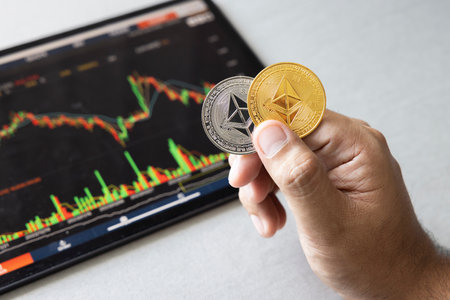 Close-up hand of man holding crypto coin on chart in tablet background. Blockchain technology finance future. Male hold Ethereum. concept about business, finance, trade, economy, banking, investment.の写真素材