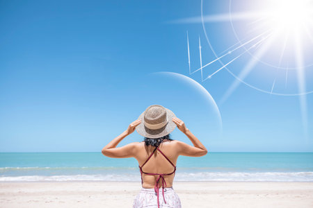 Asian model wear red swimsuit and straw hat stand on beach look view on hot day, Sun and UV rays hit the beautiful woman's protective layer. concept about of spa, sunscreen, cosmetics, health.の写真素材