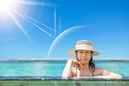 Asian model wear red swimsuit and straw hat in pool by beach looking at camera on hot day, Sun and UV rays hit beautiful woman's protective layer. concept about of spa, sunscreen, cosmetics, health.の写真素材