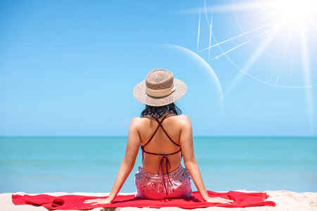 Asian model wear red swimsuit and straw hat sit on beach look view on hot day, Sun and UV rays hit the beautiful woman's protective layer. concept about of spa, sunscreen, cosmetics, health.の写真素材