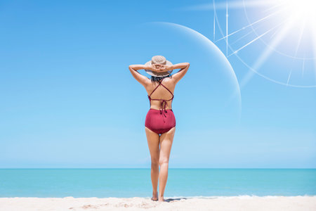 Asian model wear red swimsuit and straw hat stand on beach look view on hot day, Sun and UV rays hit the beautiful woman's protective layer. concept about of spa, sunscreen, cosmetics, health.の写真素材