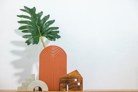 Satai Modern pottery with monstera leaves on a wooden shelf against a white wall background. Handmade pottery. Thailand's native handicrafts.の写真素材